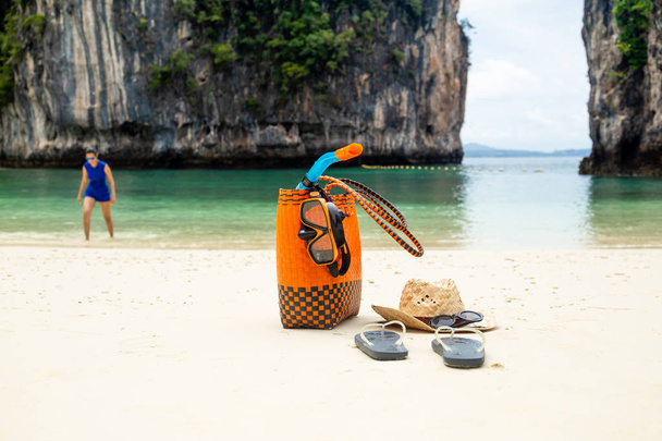 Bolsa de praia e acessórios de viagem com mulher em fundo embaçado em férias de verão. - Foto, Imagem