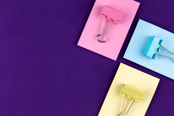 Bloc de notas con conjunto de clips de papel de colores sobre fondo púrpura.
 - Foto, Imagen