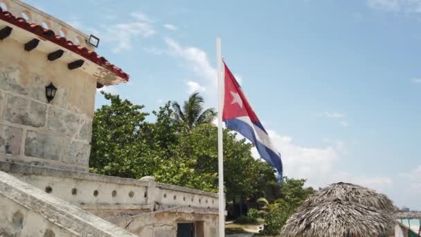 Κουβανική σημαία στην παραλία, πετώντας στον άνεμο στο φόντο του ωκεανού. Κούβα, Βαραντέρο. - Πλάνα, βίντεο