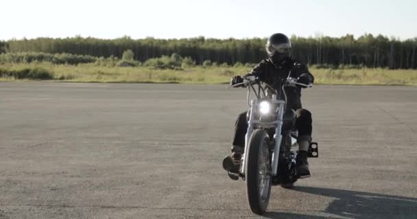Mladý muž jede na motorce v helmici na silnici, na předním pohledu. - Záběry, video