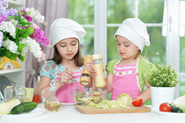 Filles mignonnes préparer une délicieuse salade fraîche dans la cuisine - Photo, image