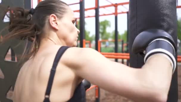 Woman boxer blows boxing bag .City boxing training outdoor . Steady shot, slow motion - Footage, Video