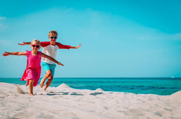 счастливые мальчик и девочка бегают играть на пляже
 - Фото, изображение