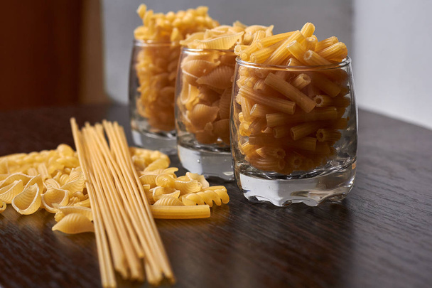 Pâtes crues sur une table en bois. La vue du haut. Spaghetti, lasagne, fusilli, nouilles besbarmak
. - Photo, image