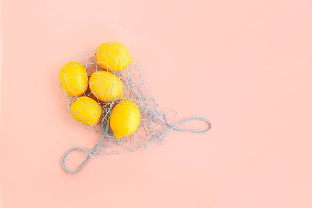 Reusable bag with lemons on pink background. Zero waste and plastic free shopping concept. - Fotoğraf, Görsel