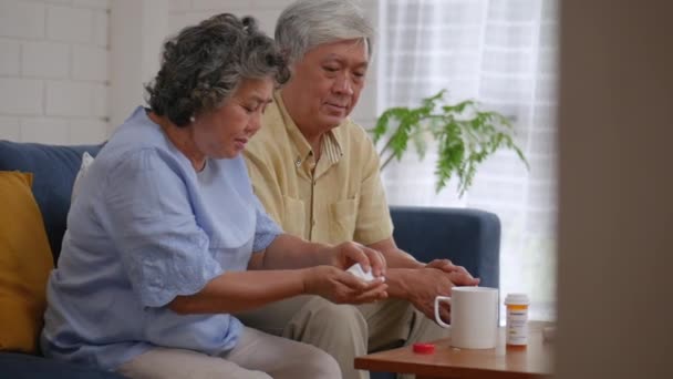 Aziatische Senior paar ouderen nemen pillen, drinkwater in woonkamer thuis. - Video