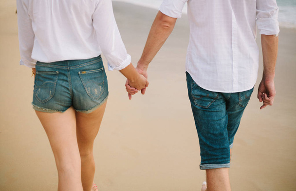 Mies ja nainen pitävät toisiaan kädestä ja kävelevät.
 - Valokuva, kuva