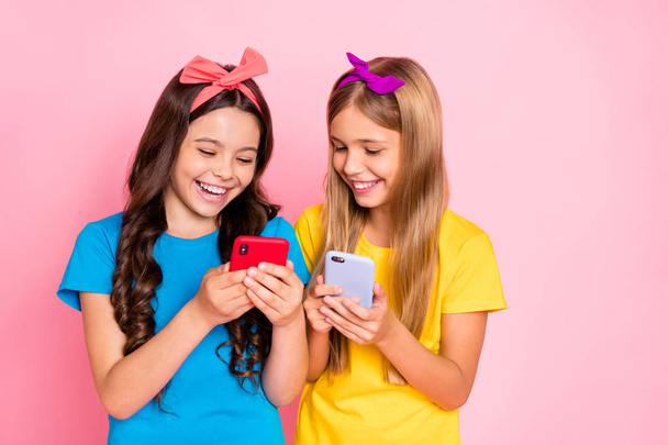 Portrait of cheerful kids laughing hold gadgets look funny information wear trendys tylish t-shirt headbands isolated over pink background - Fotó, kép