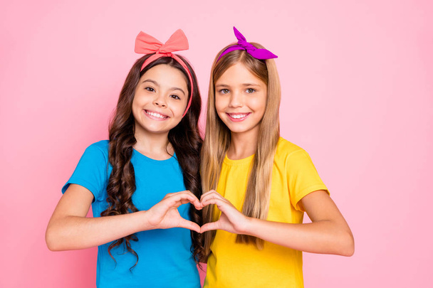 Close-up portrait of two nice attractive winsome charming cute lovely friendly cheerful cheery pre-teen girls showing heart feelings love isolated on pink pastel background - Foto, afbeelding