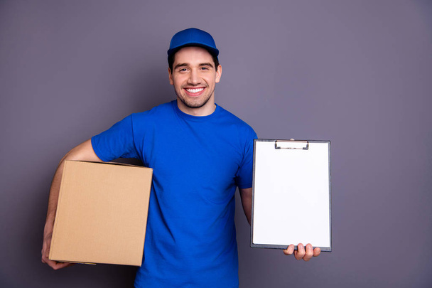 Close up photo express speed specialist he him his delivery boy hold strong arms large big parcel box accept clipboard check recipient wear blue t-shirt cap corporate suit isolated grey background - Photo, image