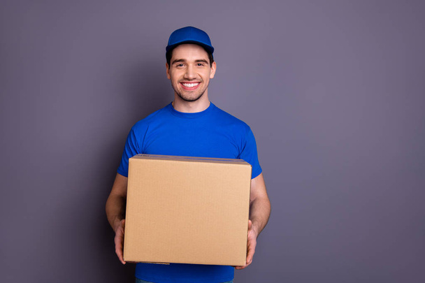Close up photo express speed specialist he him his delivery boy hold strong arms large parcel box toothy come in time accept recipient wear blue t-shirt cap corporate suit isolated grey background - Fotó, kép