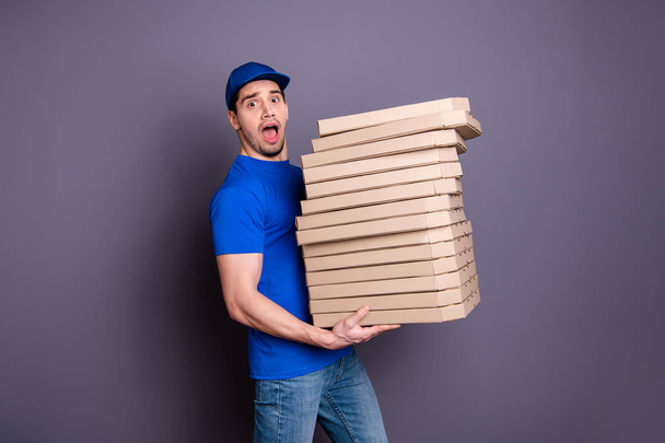Close up side profile photo amazing specialist he him his delivery boy hold arms many heavy parcel boxes unexpected big shipment move slowly wear blue t-shirt cap jeans denim isolated grey background - Fotó, kép
