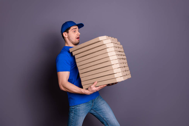 Close up side profile photo amazing specialist he him his delivery boy hold arms many heavy parcel boxes unexpected big shipment move slowly wear blue t-shirt cap jeans denim isolated grey background - Foto, Imagem