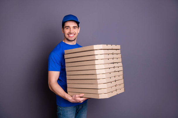 Close up side profile photo amazing specialist he him his deliveryboy hold strong arms many parcel boxes toothy smile come in time wear blue t-shirt cap jeans denim isolated grey background - Фото, изображение