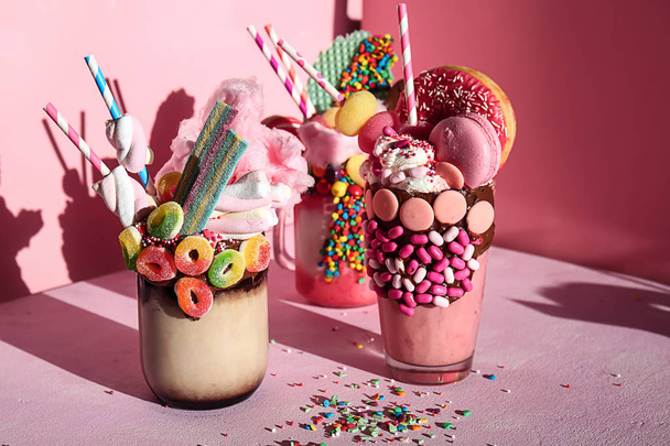 Different delicious freak shakes on color background - Photo, Image