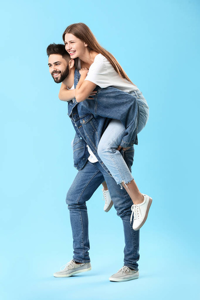 色の背景にジーンズの服でスタイリッシュな若いカップル - 写真・画像