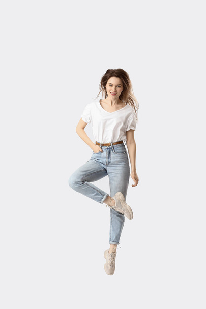 Saltando jovem mulher em jeans no fundo branco
 - Foto, Imagem