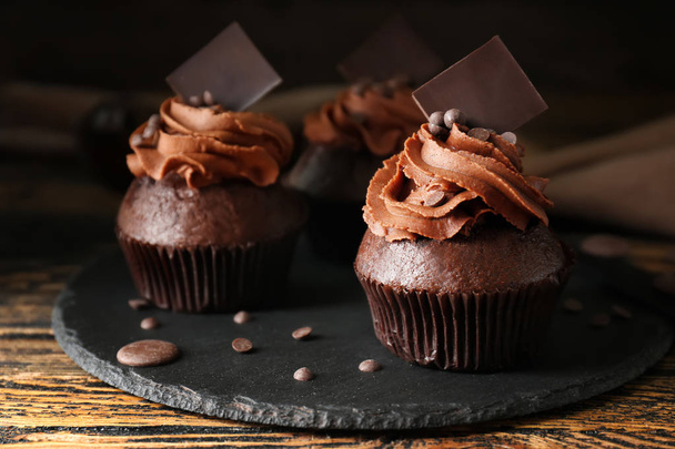Plato de pizarra con sabrosos cupcakes de chocolate sobre mesa de madera
 - Foto, Imagen