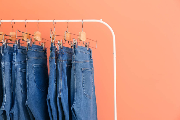 Cremalheira de roupas com calças jeans elegantes no fundo de cor
 - Foto, Imagem