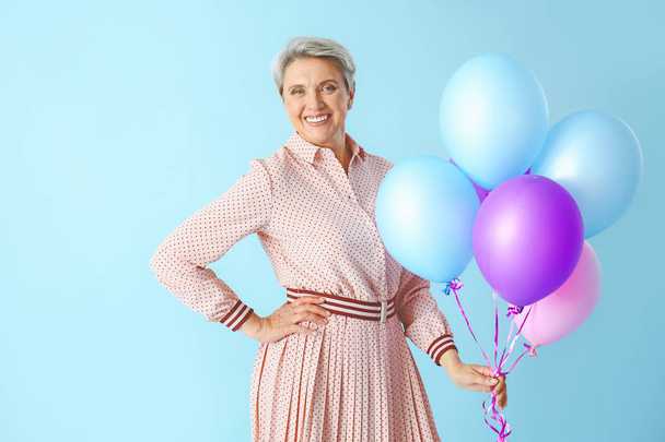 Зріла жінка з повітряними кульками на кольоровому фоні
 - Фото, зображення
