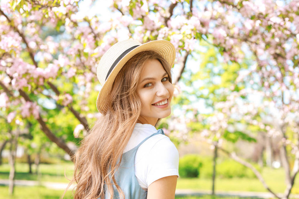 Beautiful young woman in park on spring day - Фото, изображение
