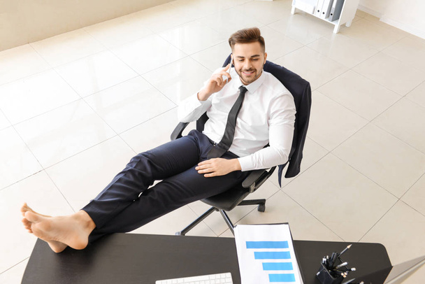 Carefree businessman talking by mobile phone in office - Foto, Imagem