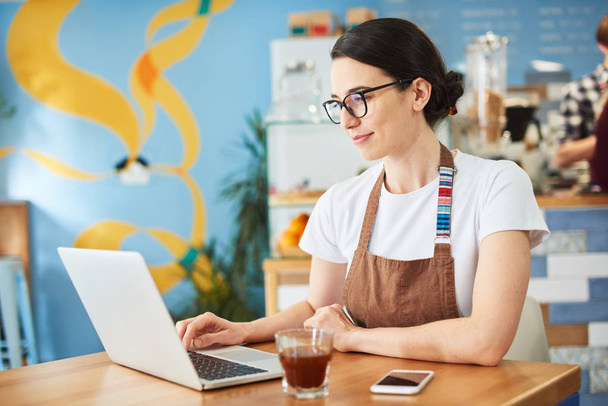 Barista wearing glasses and working on the laptop. - 写真・画像