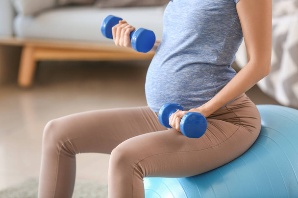 Beautiful pregnant woman with dumbbells and fitball training at home - Φωτογραφία, εικόνα