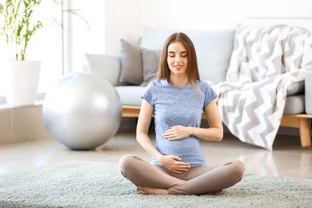 Mulher grávida bonita meditando em casa
 - Foto, Imagem