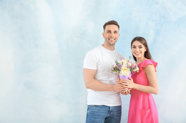 明るい背景に美しい花の花束を持つ若いカップル - 写真・画像