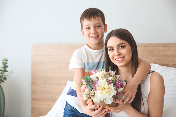 Evde güzel çiçek buketi ile genç anne ve oğlu - Fotoğraf, Görsel