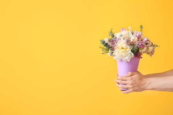 Young man with bouquet of beautiful flowers on color background - Photo, Image