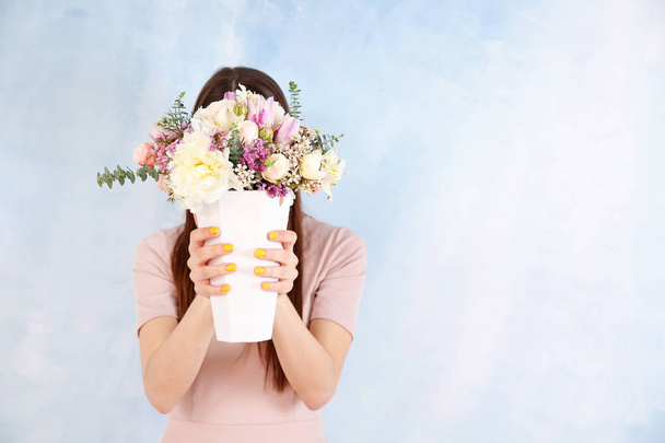 Beautiful young woman with bouquet of flowers on color background - Foto, afbeelding