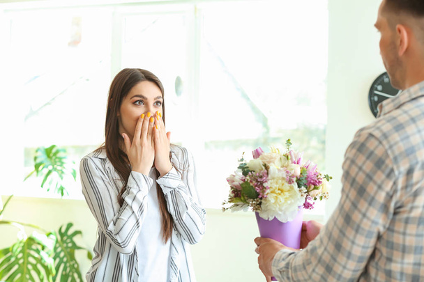 Чоловік вітає свою дружину з букетом квітів вдома
 - Фото, зображення