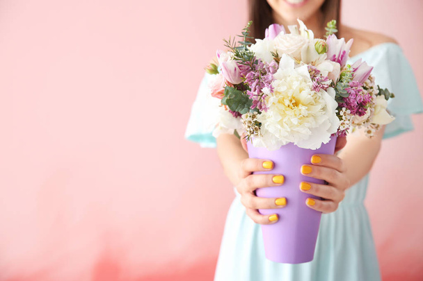 Όμορφη νεαρή γυναίκα με μπουκέτο από λουλούδια στο χρώμα φόντου - Φωτογραφία, εικόνα