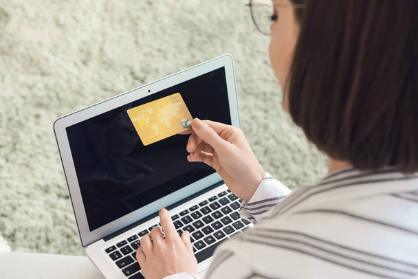 Young woman with credit card and laptop shopping online at home - Foto, Imagen
