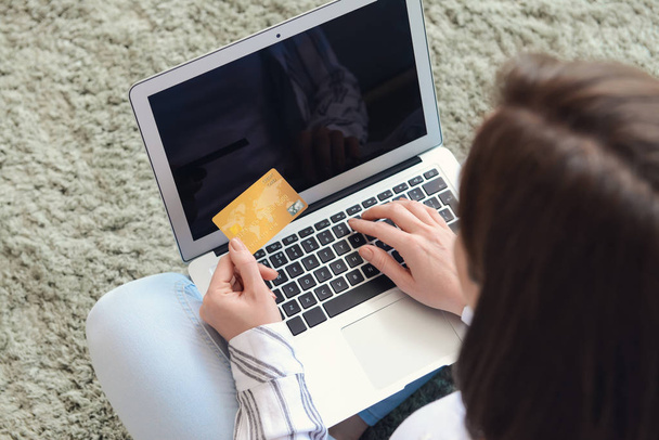 Молодая женщина с кредитной картой и ноутбука покупки в Интернете дома
 - Фото, изображение