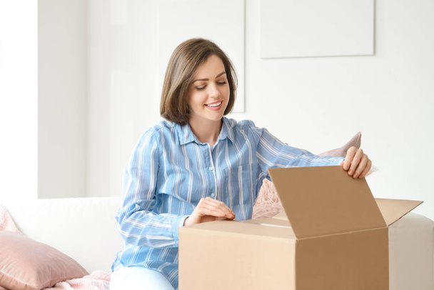 Young woman opening parcel at home - Fotó, kép