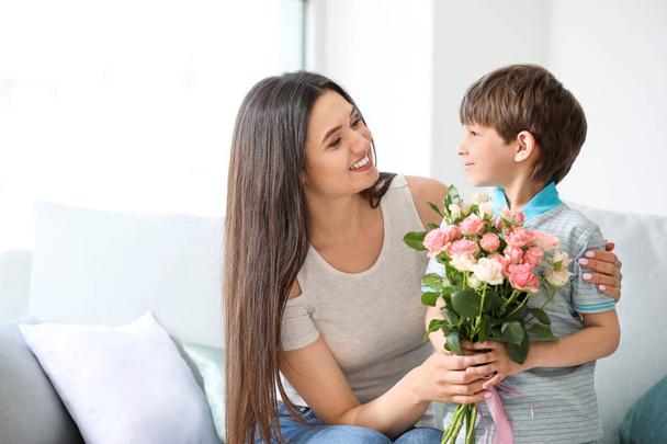 Zoon groet zijn moeder met boeket van bloemen thuis - Foto, afbeelding