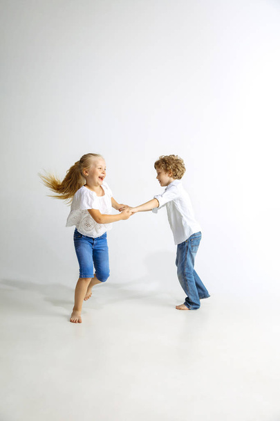 Boy and girl playing together on white studio background - Zdjęcie, obraz