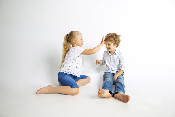 Boy and girl playing together on white studio background - Foto, imagen