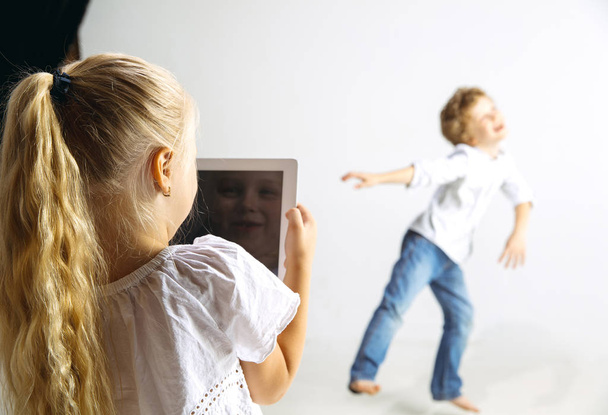 Boy and girl playing together on white studio background - Fotoğraf, Görsel