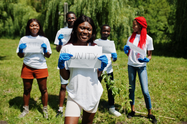 Gruppe fröhlicher afrikanischer Freiwilliger hält weiße Tafel mit Einigkeit - Foto, Bild