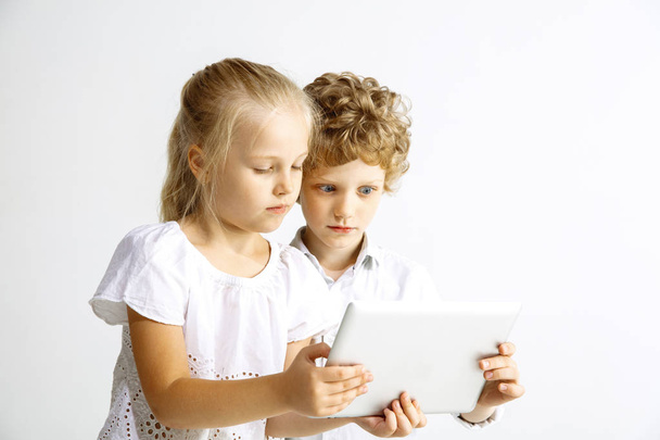 Boy and girl playing together on white studio background - Zdjęcie, obraz
