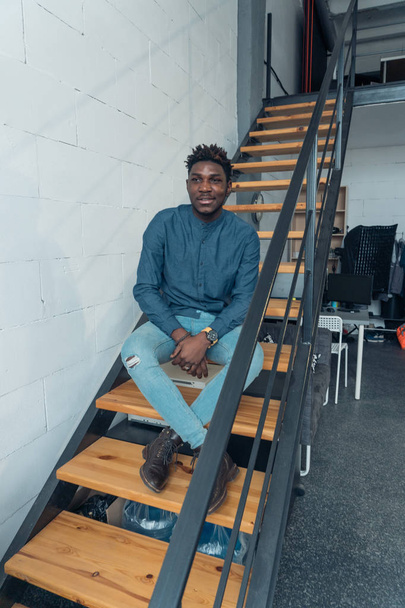 Young African guy resting on the stairs. Stylish youth - Foto, Bild