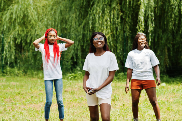 Τρεις αφροαμερικάνικες γυναίκες στο πάρκο με άσπρα μπλουζάκια. - Φωτογραφία, εικόνα