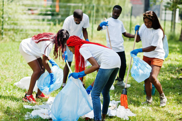 Group of happy african volunteers with garbage bags cleaning are - 写真・画像