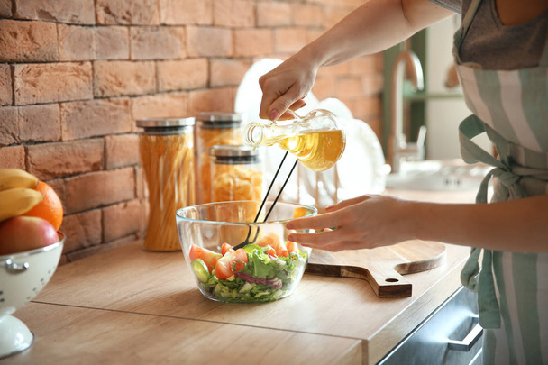 Красивая молодая женщина делает свежий салат на кухне
 - Фото, изображение