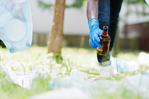 Hand of african american man picking up bottle into garbage bags - Foto, Imagen