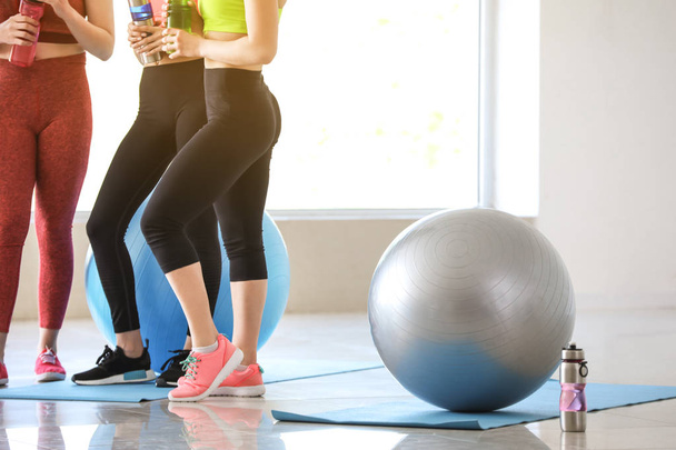 Young sporty women with fitballs drinking bottle in gym - Photo, Image